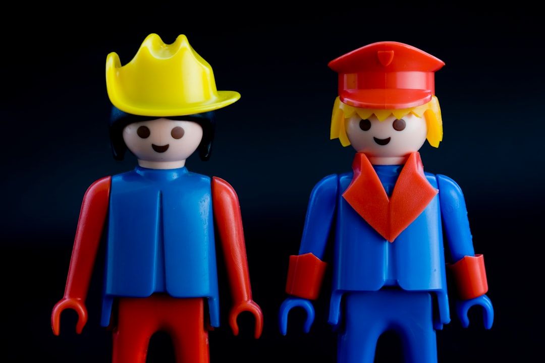 Twee Playmobil-poppetjes, een met cowboyhoed, de ander in brandweeruniform, symboliseren kinderkleding.